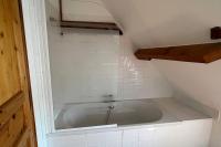 a bath tub in a bathroom with a white tiled floor at La Reinette du Verger 9 d&#39;Arry 1 in Arry