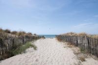 a sandy beach with a fence and the ocean at SOWELL RESIDENCES Les Sablons in Le Grau-du-Roi