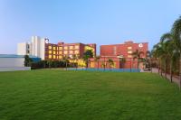 un parque con palmeras y edificios al fondo en Fortune Park Airport Road, Hubballi - Member ITC Hotels&#39; Group, en Hubli