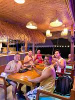 a group of people sitting around a table in a restaurant at Banig Beach Resort El Nido in El Nido