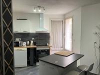 a kitchen with white cabinets and a black counter top at Appartement all in grey in Agen