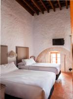 two beds in a room with a tv on the wall at Hotel Tugasa Convento San Francisco in Vejer de la Frontera
