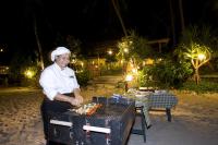 高兰Vacation Village Phra Nang Lanta - SHA Extra Plus的海滩上的烧烤架上的妇女烹饪食物