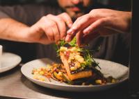 Um homem está a preparar um prato de comida numa mesa. em Keenans Boutique Hotel em Termonbarry