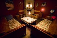 a living room with two beds and a fireplace at Hôtel des Alpes - Skiers & Bikers Lodge in La Grave