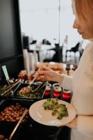 a woman is preparing a plate of food at Hotel Saltic Resort & Spa Grzybowo in Kołobrzeg