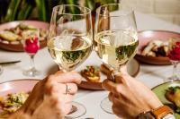 two people holding glasses of white wine at a table at InterContinental Montreal by IHG in Montréal