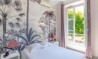 a bedroom with a bed with a tropical wallpaper at Hotel Les Palmiers in Sainte-Maxime