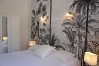 a bedroom with a bed with a wallpaper with palm trees at Hotel Les Palmiers in Sainte-Maxime