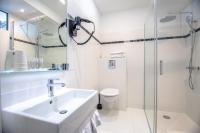 a white bathroom with a sink and a shower at Hotel Les Palmiers in Sainte-Maxime