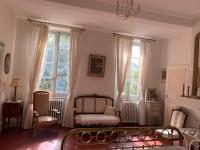 a living room with a couch and two windows at Le Moulin du Carla in Lavaur