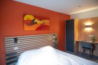 a bedroom with an orange wall with a bed and a desk at L&#39;Orée des Sources in Volvic