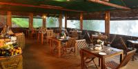 蒙纳自然区丛林度假村的有木桌椅和窗户的餐厅