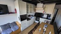 a kitchen with white cabinets and a wooden table at Rijksmonument Havenzicht, met zeezicht, ligging direct aan zee en centrum in Vlissingen