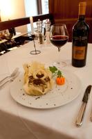 Appartamenti LEON D'ORO في ريفا ديل غاردا: طبق طعام على طاولة مع كأس من النبيذ