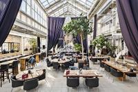 Un restaurante con mesas y sillas y un techo de cristal. en Best Western ToRVEhallerne, en Vejle