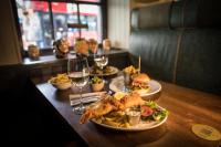 a table with plates of food and glasses of wine at The Pride of Paddington in London