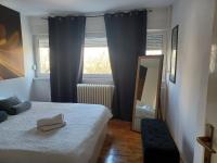 a bedroom with a bed and a mirror and a window at Apartment M&amp;A in Osijek