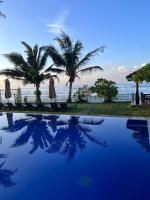 a swimming pool with palm trees and the ocean at Surf Station in Ahangama