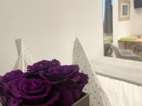 a bouquet of purple roses in a box on a bed at Ferienzimmer Adalonia in Greifswald