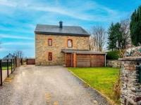 a stone house with a garage and a driveway at Lovely holiday home in Gouvy with sauna in Gouvy