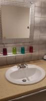 a bathroom sink with four colored cups on a shelf at Domaine Lagardelle Rocamadour in Rocamadour