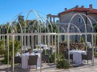 Un restaurante con mesas y sillas blancas y un edificio. en Villa Cavalieri Country Hotel, en Pula