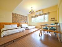 a bedroom with two beds and a table in it at Hejia B&amp;B in Hualien City