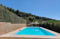 a swimming pool in a garden with a stone wall at Mas Chamarel à Sanary-sur-Mer au milieu des vignes et oliviers in Sanary-sur-Mer