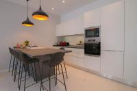 a kitchen with white cabinets and a table with stools at NAPOLEON Luxurious renovated apartment 1min from Palais in Cannes