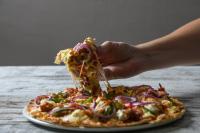 een persoon die een stuk pizza eet op een tafel bij San Lameer Villa 3303 - 2 Bedroom Classic - 4 pax - San Lameer Rental Agency in Southbroom