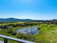 a view from a balcony of a field and a pond at Apartment Stanatura-4 by Interhome in Porto-Vecchio