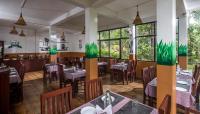 ein Restaurant mit Tischen, Stühlen und Fenstern in der Unterkunft Spice Jungle Resort in Munnar