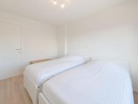 two beds in a room with white walls at Apartment De Zeegloed by Interhome in De Haan
