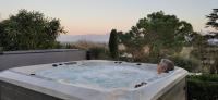 a man in a hot tub on a patio at La Villa Moursoise 4 Etoiles in Mours-Saint-EusÃ¨be