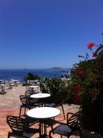 a group of tables and chairs with the ocean in the background at Village Naturiste La Chiappa in Porto-Vecchio