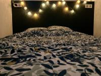 a bed with a black and white comforter and lights at Appartement avec terrasse et parking gratuit accolé in Montbéliard