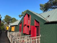 a green and red house with a wooden deck at Le Cocon Cap Forêt in Lège-Cap-Ferret