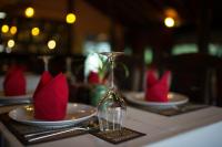 une table avec deux assiettes, des serviettes rouges et un verre à vin dans l'établissement Kouprey Hotel, à Siem Reap