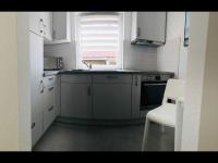 a kitchen with white cabinets and a sink and a chair at Ferienhaus Live Deluxe in der schönen Uckermark in Meyenburg
