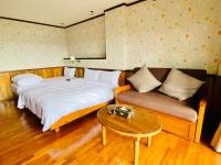 a bedroom with a bed and a couch and a table at 見晴花園山莊Sunshine Villa in Ren&#39;ai