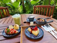 Una mesa de madera con platos de comida y una bebida. en The Bedrooms Maeklong and Services Apartment, en Samut Songkhram
