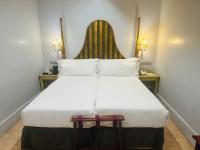 a bedroom with a large white bed with a headboard at Sacristia de Santa Ana in Seville