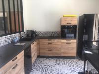 a kitchen with wooden cabinets and a black refrigerator at Villa Emma 10 &#47; 12 personnes in Grignan