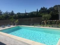 a swimming pool in a yard with two chairs at Villa Emma 10 &#47; 12 personnes in Grignan