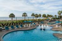 einen Pool am Strand mit Stühlen und dem Meer in der Unterkunft Courtyard by Marriott Myrtle Beach Oceanfront in Myrtle Beach