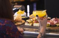 a woman holding up a drink in front of a table of food at Campanile Nancy Centre - Gare in Nancy