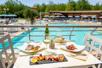 una mesa con comida y vino junto a una piscina en Camping Village Baia Azzurra, en Castiglione della Pescaia