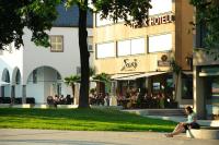 una mujer sentada en un banco frente a un edificio en Park Hotel, en Schweinfurt