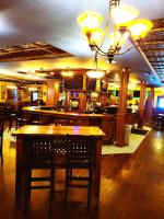 un restaurante con barra con mesas y sillas en Royal Duke Hotel, en Okotoks